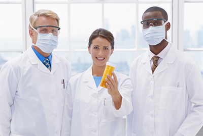 Three doctors standing with female doctor holding prescription medication, portrait